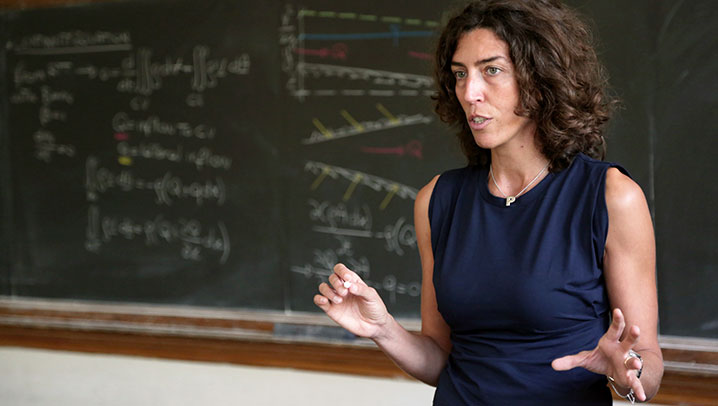 Professor in front of the word courage written on a classic black board with students learning